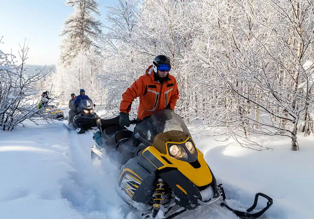 group of snowmobile riders on a snowy trail