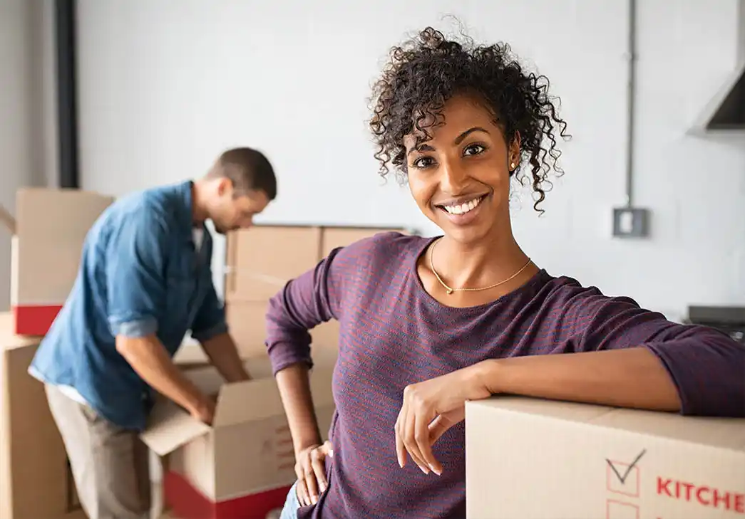 Woman leaning on cardboard box while moving house