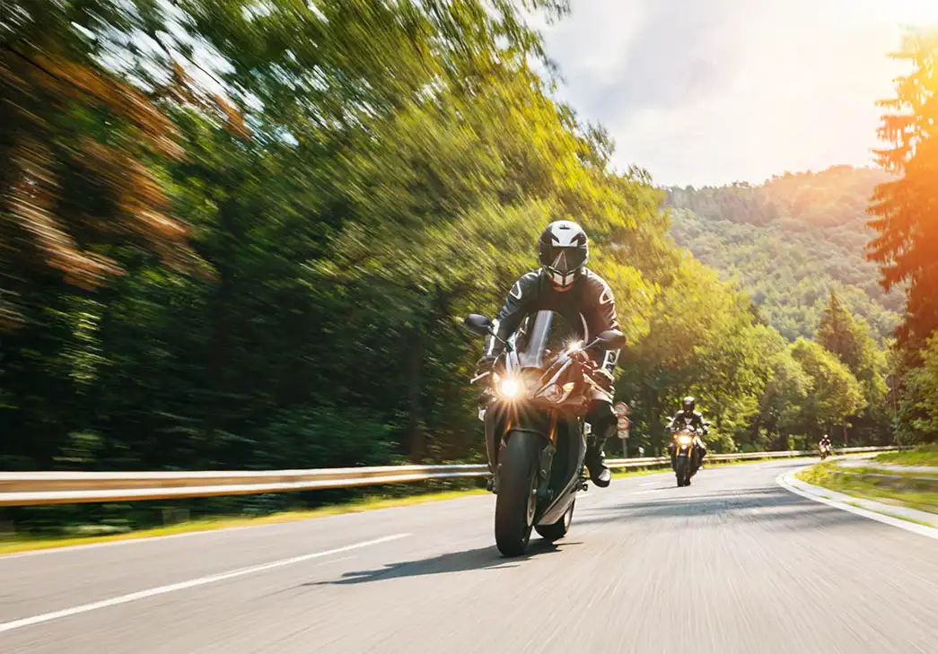 group of motorcyclists riding down a country highway