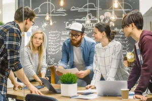 Team Meeting of Developers, They Lean on the Table and Look at the Results Shown on the Laptop. Creative Young People in Stylish Office Environment