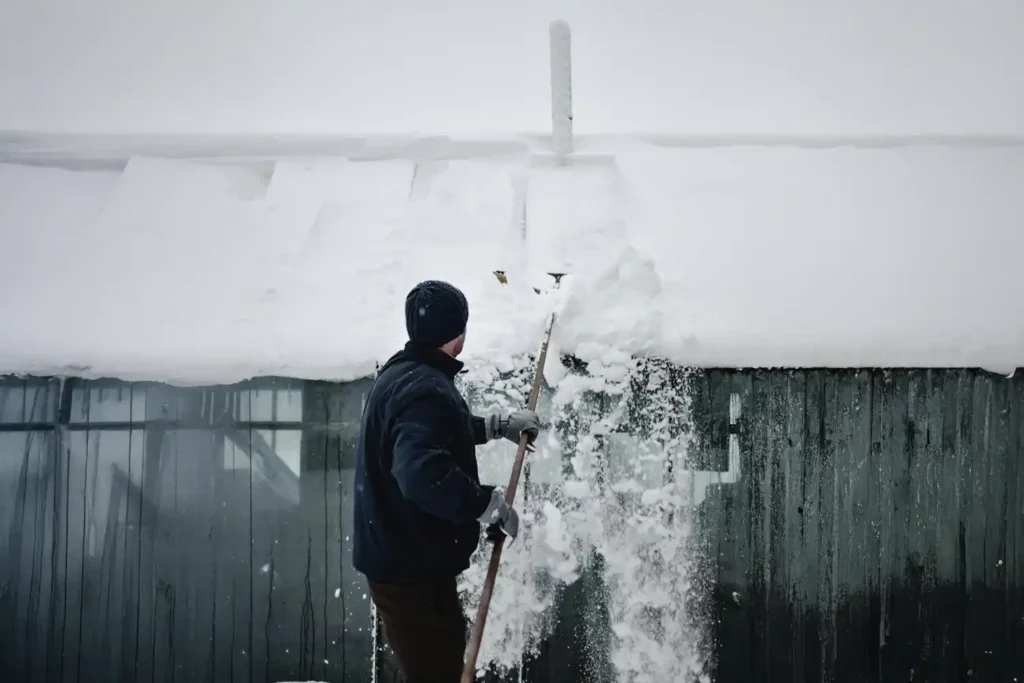 Man cleaning deep snow off a roof